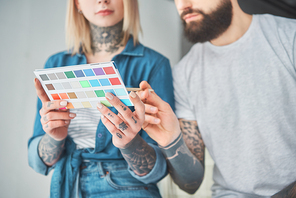 cropped shot of young tattooed couple holding palette of colors and choosing color for home improvement