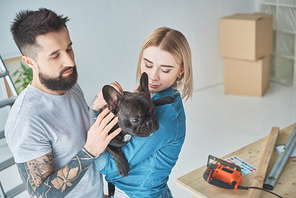portrait of tattooed couple with french bulldog at new home