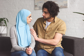 muslim boyfriend hugging girlfriend in hijab in living room