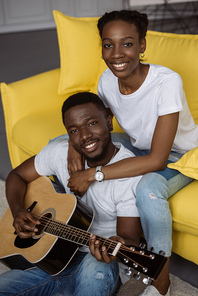 happy young african american couple with acoustic guitar smiling at camera