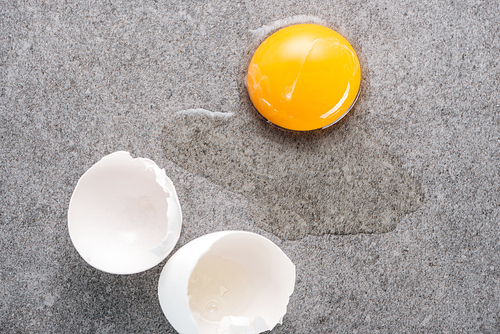 close up of raw smashed egg with yolk and protein on grey background