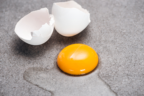 close up of raw smashed egg with yolk and protein on grey textured background