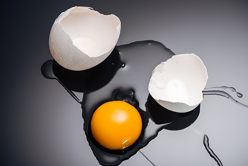close up of fresh smashed chicken egg with yolk, protein and eggshell on black background