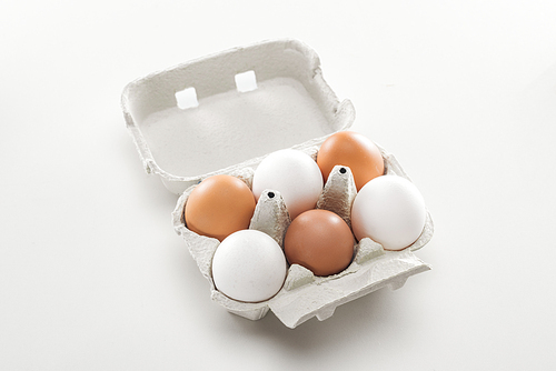 raw white and brown chicken eggs in carton box on white background