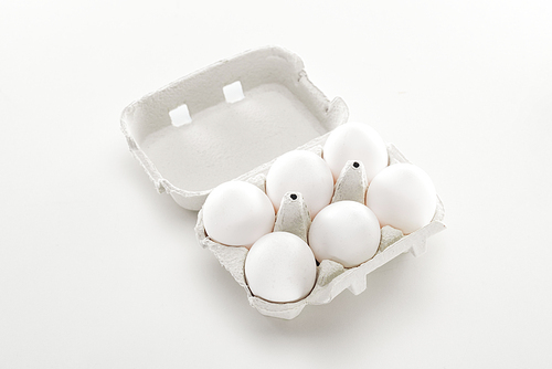 raw white chicken eggs in cardboard box on white background