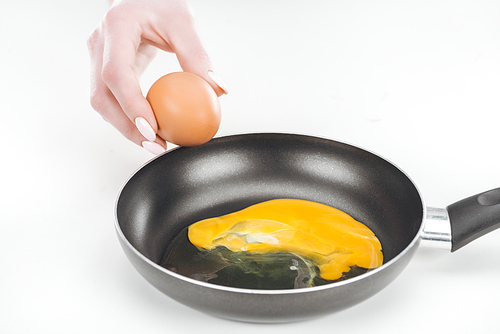 cropped view of woman preparing scrambled eggs in pan on white background