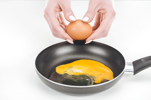 partial view of woman preparing scrambled eggs in pan on white background