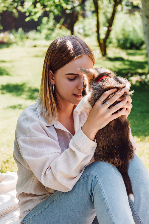 blonde girl with closed eyes holding cute puppy in green garden