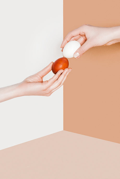cropped view of people with easter eggs on beige and white minimalistic background