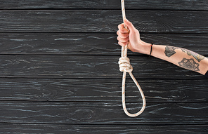 partial view of female hand with marine rope with knot on dark wooden surface