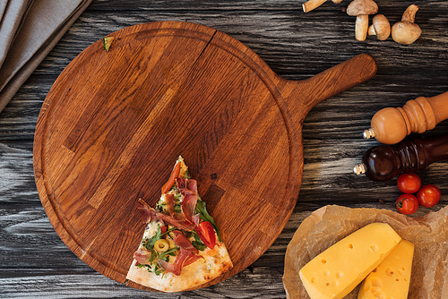 top view of single slice of tasty pizza on wooden cutting board