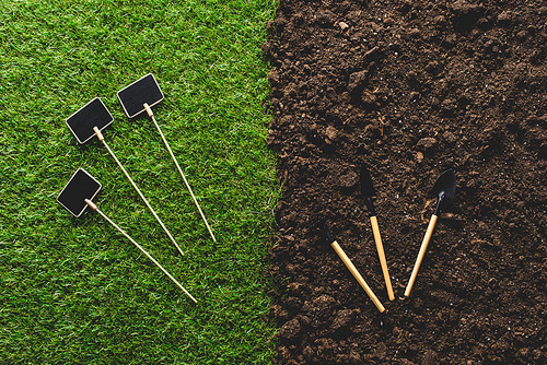 top view of empty blackboards on grass and gardening tools on soil