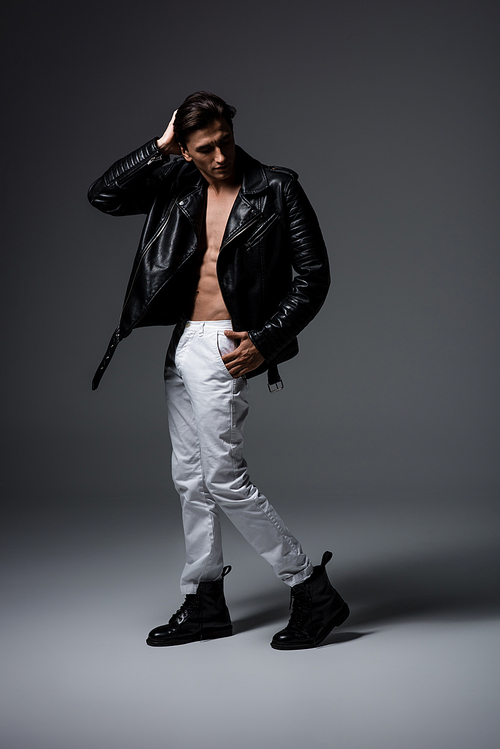 shirtless man in white jeans and black leather jacket| on grey