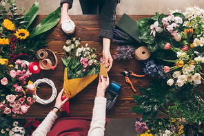 cropped image of customer giving florist credit card to pay for bouquet
