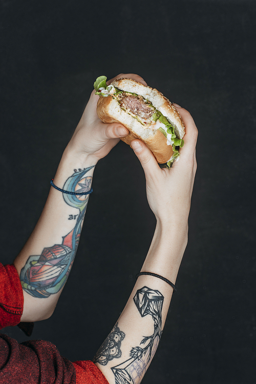 cropped view of tattooed girl eating hamburger