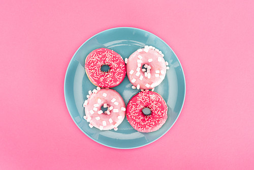 top view of glazed doughnuts on plate isolated on pink