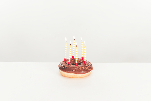 delicious glazed doughnut with birthday candles on white table