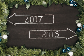 top view of 2017| 2018 year signs with christmas decorations around on dark wooden surface