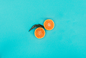 top view of pieces of orange and leaf isolated on blue