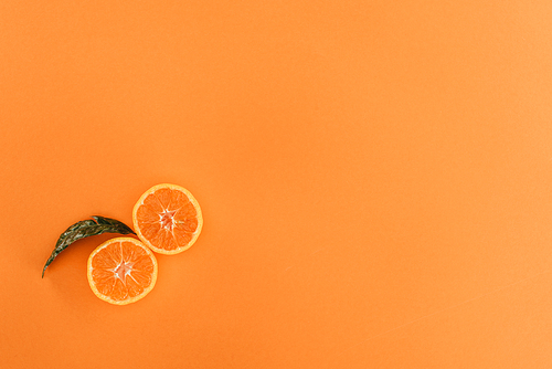 top view of pieces of orange and leaf isolated on orange