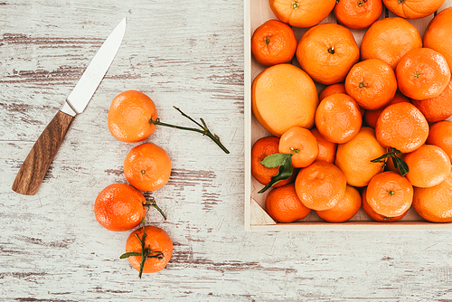 flat lay with tangerines in box and knife on shabby wooden tabletop