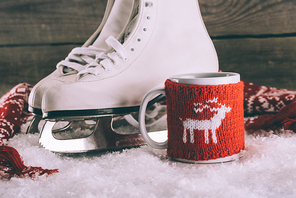 pair of white skates with cup with knitted ornament and scarf