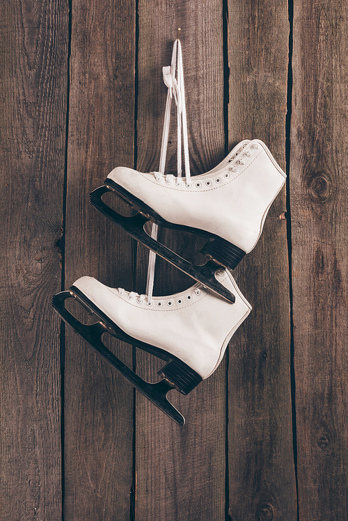 pair of white skates hanging on wooden wall with shoelaces
