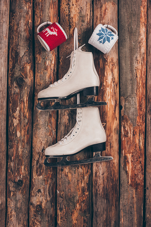 two cups and pair of white skates hanging on wooden wall