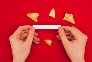 cropped shot of woman opening traditional fortune cookie| Chinese New Year concept