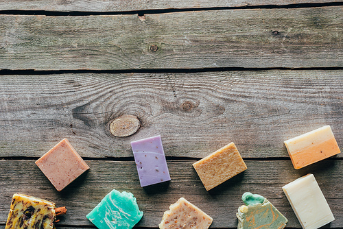 top view of different natural homemade soap on wooden surface