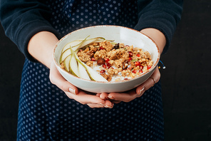 cropped image of female cook holding bowl with granola in hands