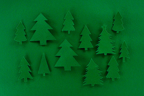 top view of green decorative paper christmas trees on green background