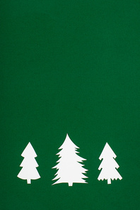 top view of decorative paper christmas trees on green background with copy space