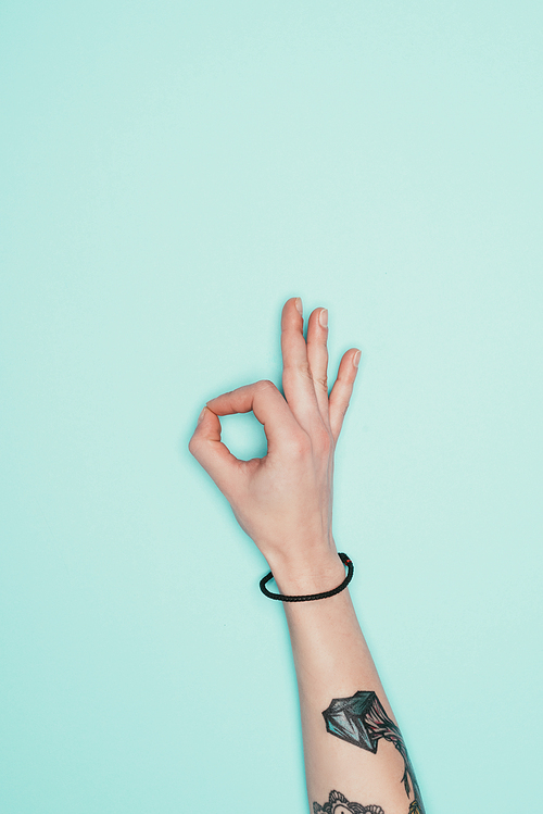 cropped shot of woman showing okay sign isolated on turquoise