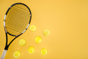 Tennis racket with balls isolated on yellow