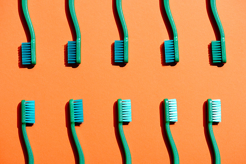 minimalistic background with green toothbrushes| on orange