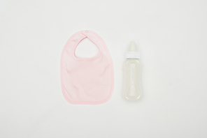 top view of baby bib and bottle of milk isolated on white