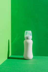 plastic baby bottle with milk on green