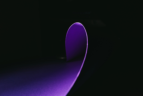 warping purple paper in shape of wave on black