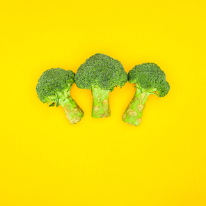 top view of fresh green organic broccoli isolated on yellow