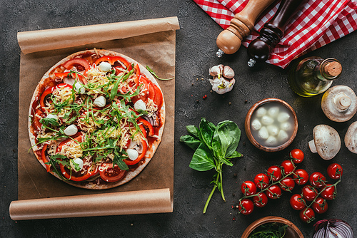 top view of delicious pizza with ingredients on concrete table