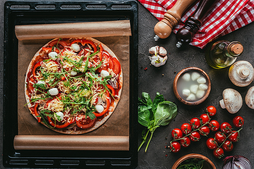 top view of freshly baked pizza with ingredients on concrete table