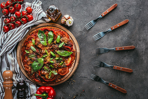 top view of delicious pizza with forks on concrete table