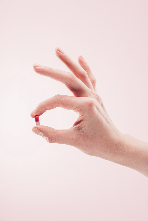 partial view of woman holding medicine in hand isolated on pink