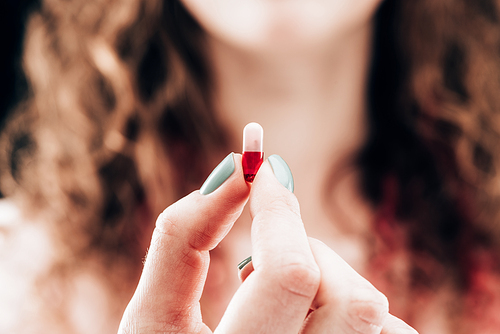 partial view of woman showing pill in hand