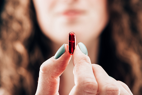 partial view of woman showing pill in hand