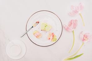 top view of pieces of cake on plate with fork| flowers and cup of milk on tabletop