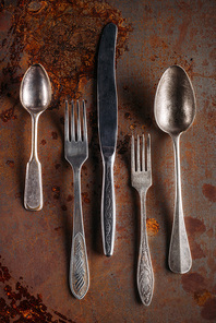 Vintage spoons and forks with knife on rusted background
