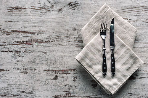 Metal fork with knife on napkin on wooden table