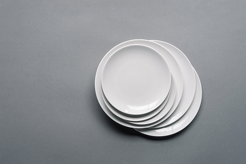 Stack of white porcelain plates on grey background